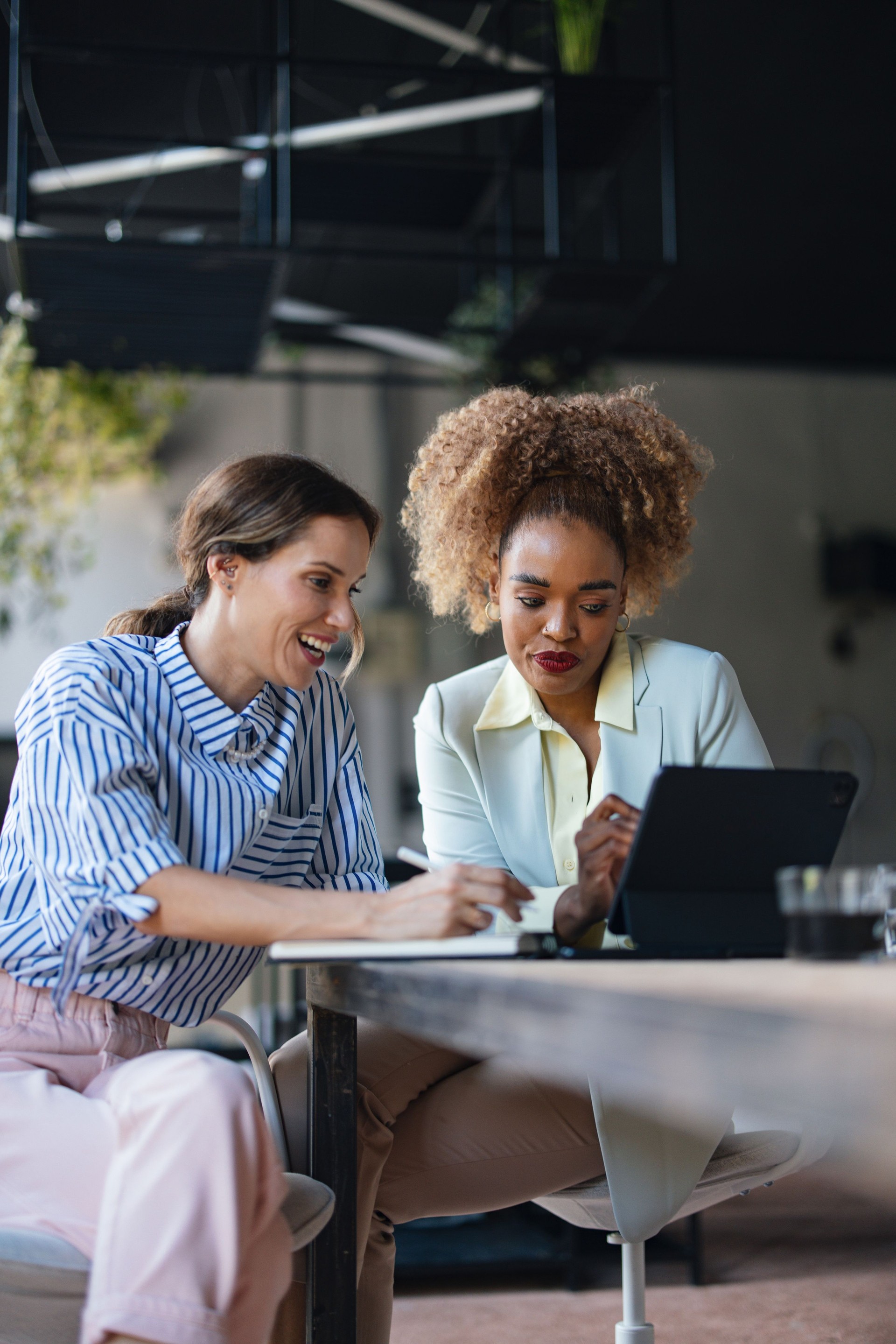 Two Multiethnic Happy Businesswomen Working In The Office Using Their Computer